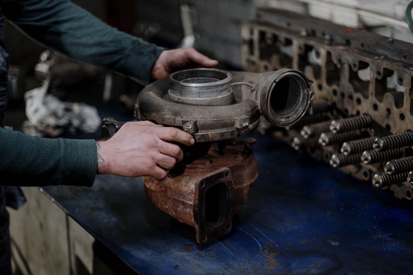 Mechanic's hands repairing a turbocharger on a workbench